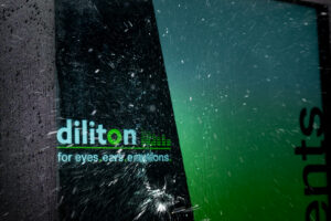 Nahaufnahme eines eingeschalteten digitalen Outdoor-Kundenstoppers im Regen, auf dessen IP 65 geschützten Display mit dem Logo „diliton“ deutlich Wassertropfen zu sehen sind.