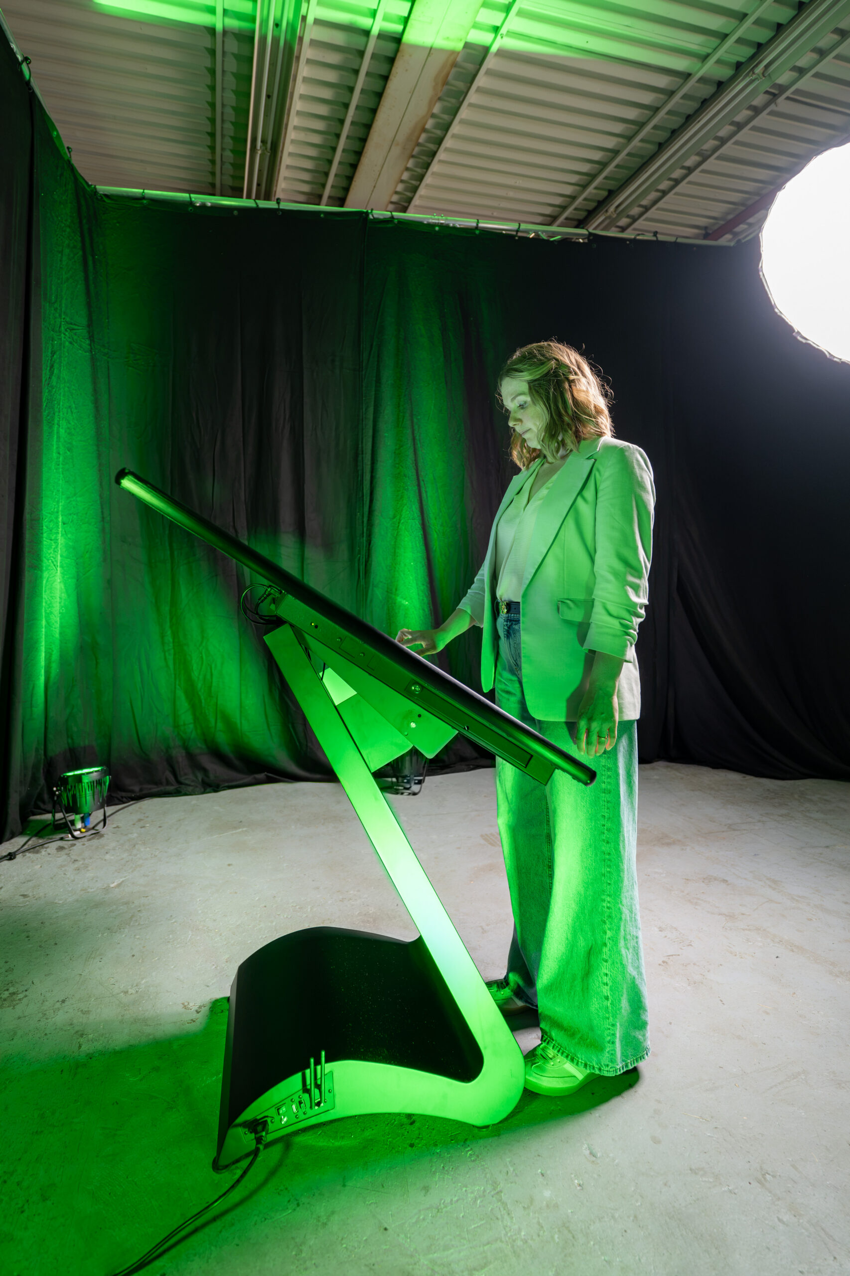 Seitenansicht einer Frau im hellen Blazer bei der Bedienung einer horizontalen Kiosk-Stele mit einem ergonomisch geschwungenen S-Sockel und angepasstem Neigungswinkel im Fotostudio.