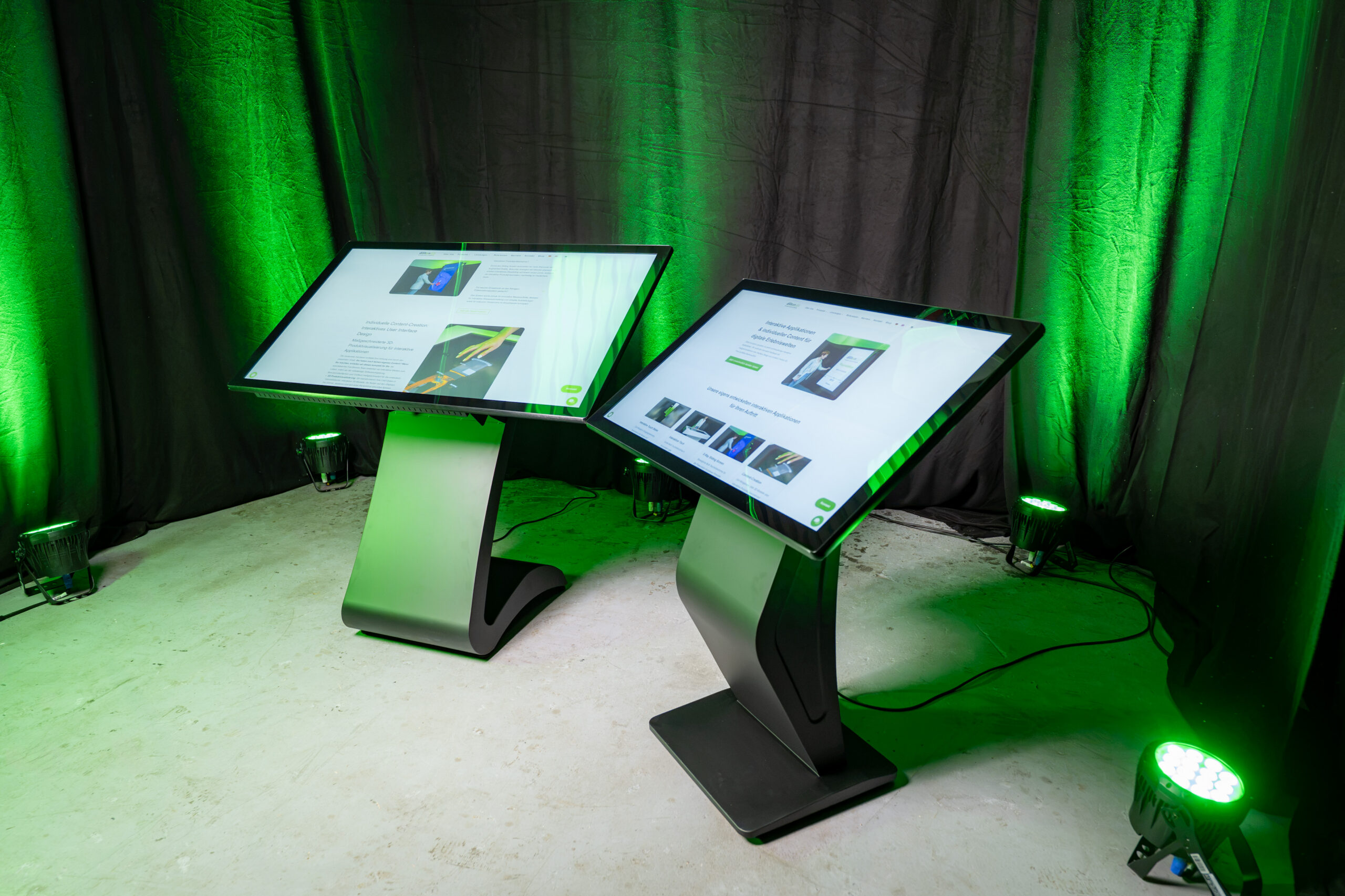 Perspektivische Studioaufnahme zweier horizontaler Touch Terminals: Im Vordergrund steht die Kiosk Stele mit einem massiven K-Sockel, dahinter ist das Modell mit dem geschwungenen S-Sockel deutlich zu erkennen.