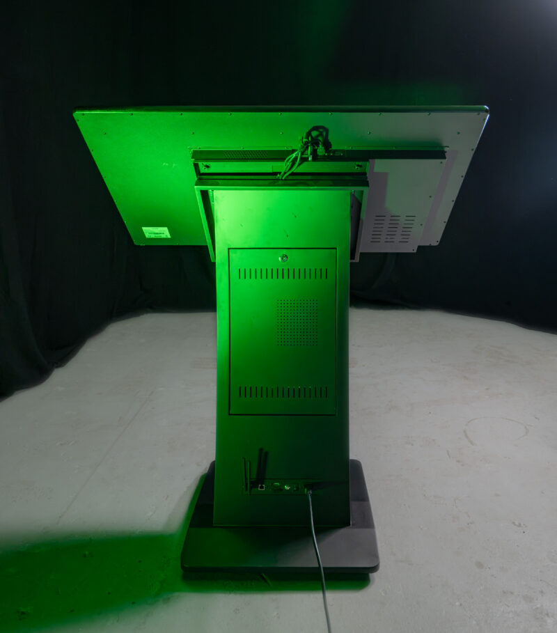 Rückansicht einer interaktiven, horizontalen Kiosk-Stele mit einem massiven K-Sockel Standfuß, integriertem PC und Kabelanschlüssen im Studio.