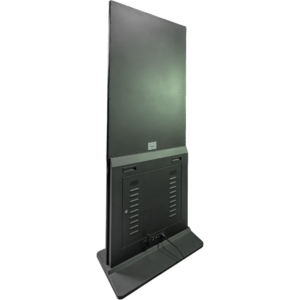 Die Rückseite einer schwarzen digitalen Touch-Stele, fotografiert aus einer schrägen Perspektive vor weißem Hintergrund. Die hochwertige Infostele zeigt eine geschlossene, matte Metallrückwand im oberen Bereich. Im unteren Bereich befindet sich eine abschließbare Wartungsklappe mit Lüftungsschlitzen für die Technik. Am soliden Standfuß der digitalen Touch-Stele sind Anschlüsse sowie ein eingestecktes Stromkabel zu sehen.