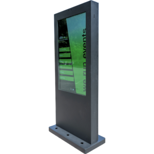 Seitenansicht einer schwarzen, freistehenden digitalen Outdoor-Touchstele. Das Gehäuse ist leicht schräg von der Seite fotografiert, sodass die Tiefe der Kiosksäule sichtbar wird. Auf dem hochkant ausgerichteten Bildschirm spiegelt sich eine grüne Außenumgebung.